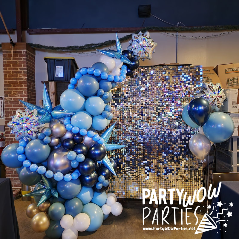 A large, blue snowflake balloon arch is attached to a shimmer wall to create a photo selfie area in the Craft Bastard Brewery in Knoxville, Tennessee
